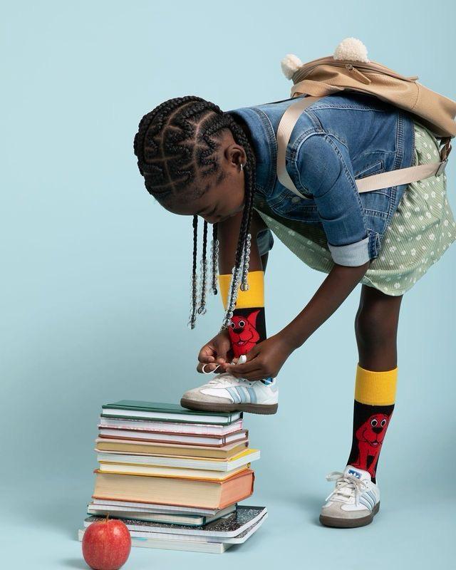 Enfant nouant ses lacets, pied sur une pile de livres
