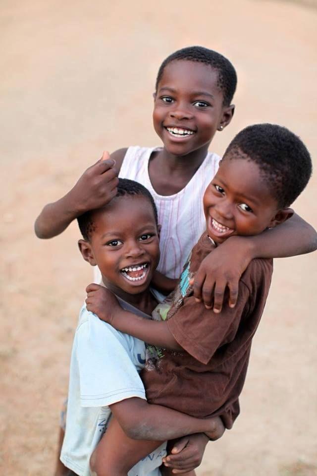 Trois enfants souriants, réunis dans les bras les uns des autres