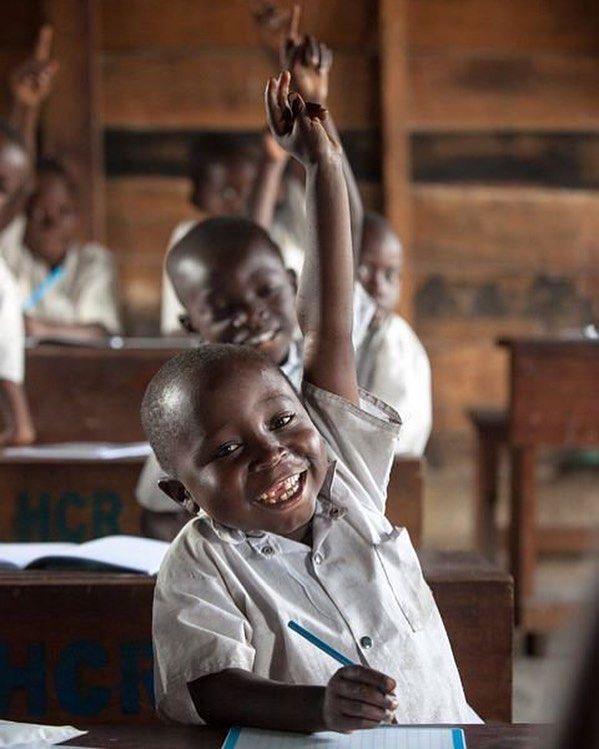 Enfant souriant lève la main dans une salle de classe